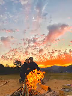 Casal ao redor da fogueira ao entardecer